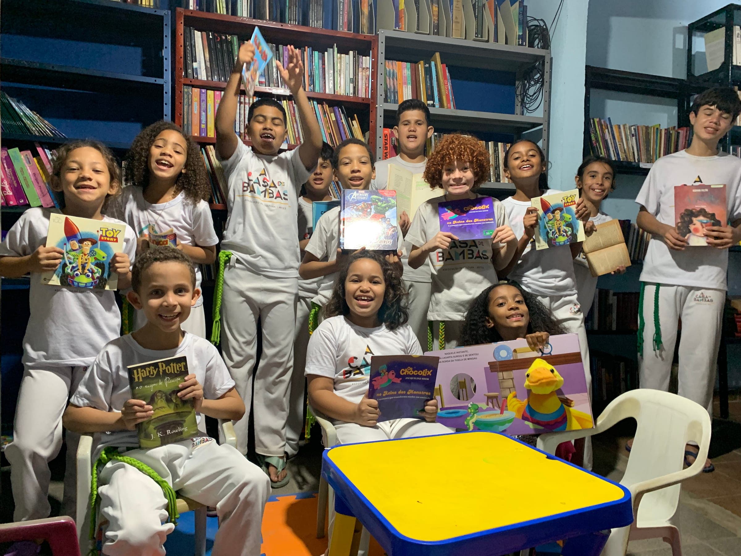 Crianças da Casa de Bambas segurando livros na biblioteca comunitária